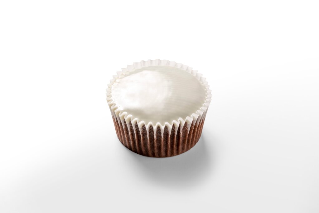 Chocolate cupcake in a paper cup with a smooth, flat white layer of chocolate compound on top