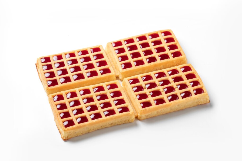 Four waffles with red jam deposited in every square cavity