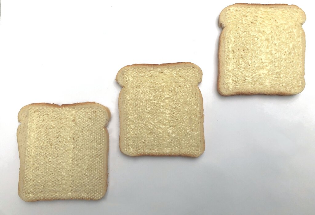 Three slices of white bread covered with a thin layer of spread in fine beads